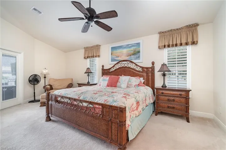 Bedroom featuring visible vents, light colored carpet, baseboards, and lofted ceiling