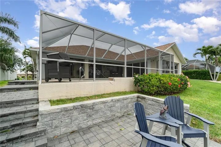 Rear view of property featuring a patio area, a yard, glass enclosure, and stucco siding