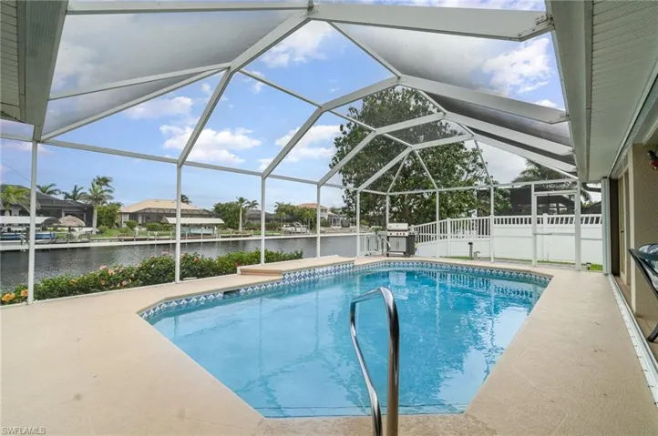 Pool featuring a water view, a patio area, and glass enclosure