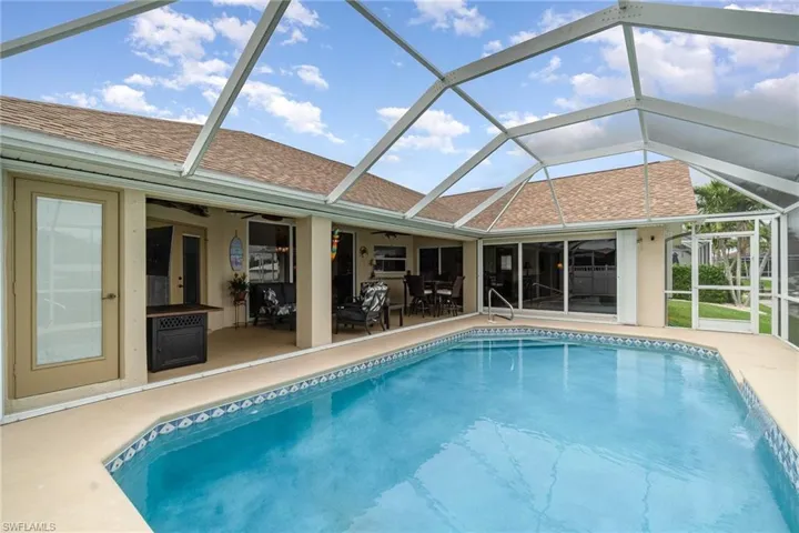 Pool featuring a patio, glass enclosure, and ceiling fan