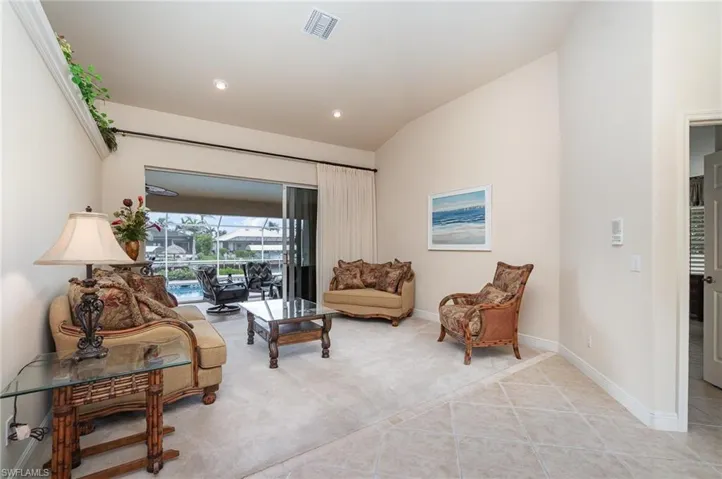 Living area with light tile patterned floors, baseboards, visible vents, light colored carpet, and lofted ceiling