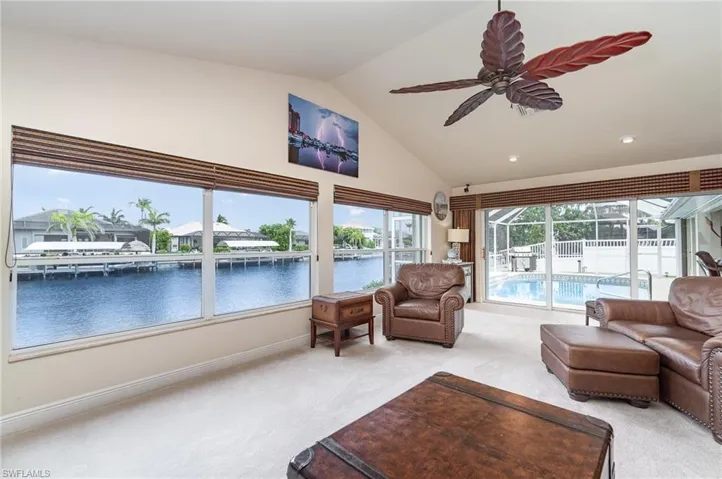 Living area featuring a water view, ceiling fan, light colored carpet, and baseboards