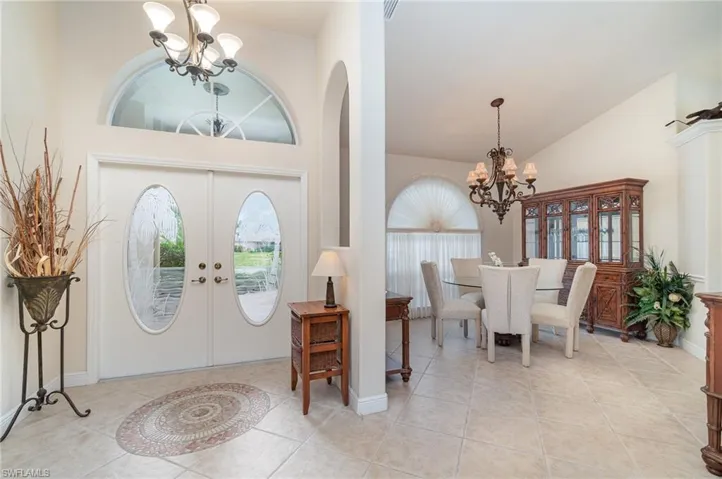 Foyer featuring light tile patterned floors, high vaulted ceiling, arched walkways, and a notable chandelier