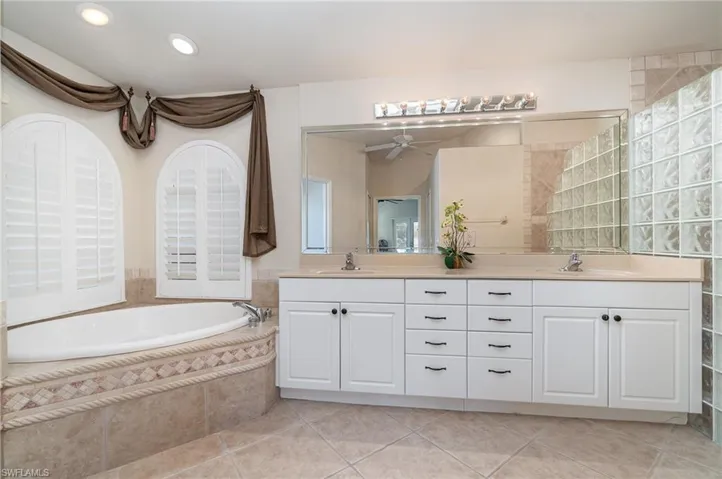 Bathroom with tile patterned floors, double vanity, a bath, and a sink