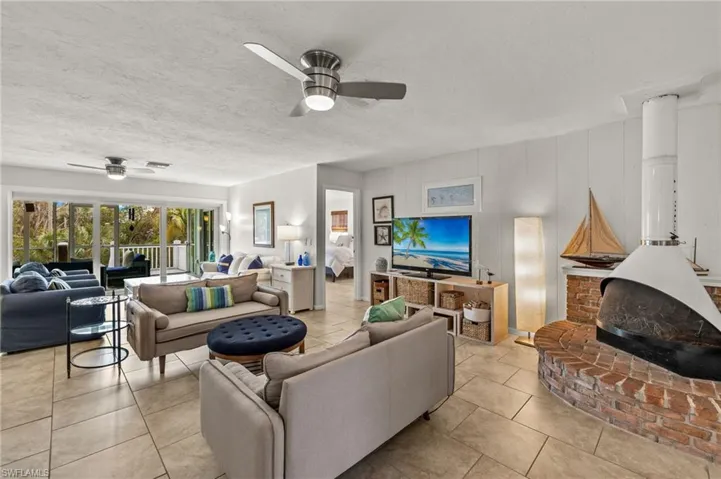 Living area with a wood stove, a ceiling fan, a textured ceiling, and tile patterned flooring