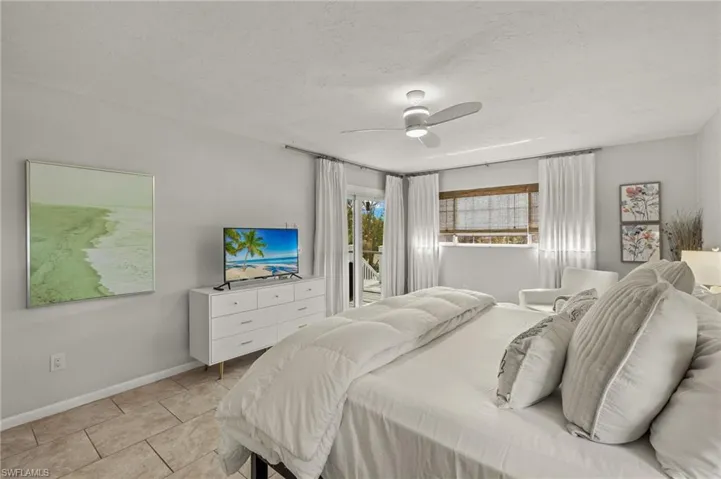 Bedroom with access to exterior, a textured ceiling, a ceiling fan, and light tile patterned floors
