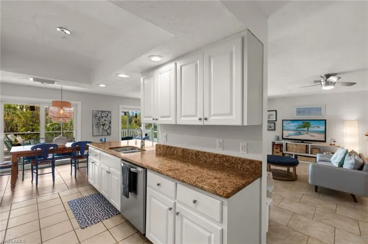 Kitchen featuring white cabinetry, recessed lighting, a tray ceiling, hanging light fixtures, and dark stone countertops