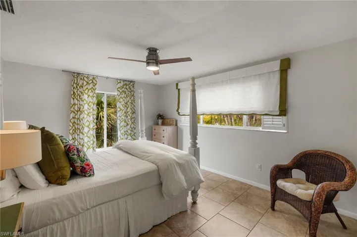 Bedroom with multiple windows, tile patterned floors, and a ceiling fan