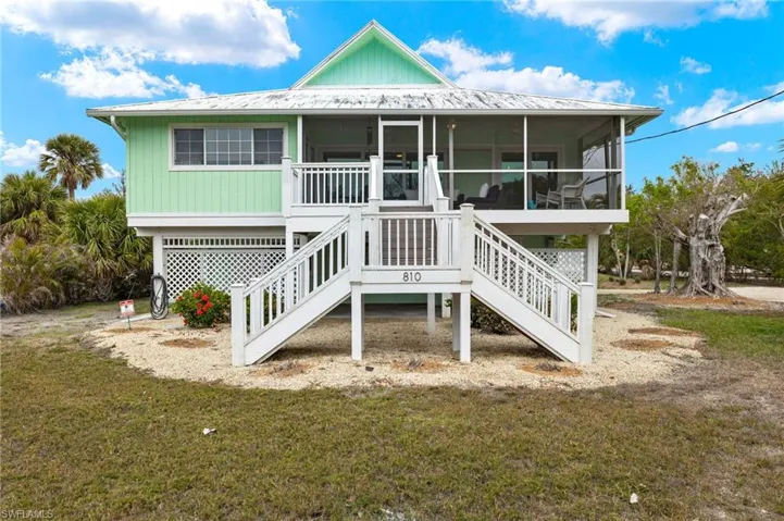 View of front of home featuring a sunroom, stairway, a metal roof, and a front yard