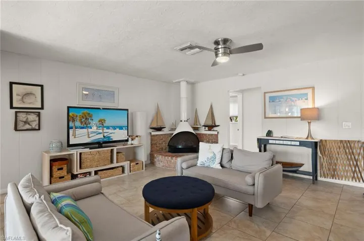 Living area with a wood stove, wood walls, ceiling fan, and a textured ceiling