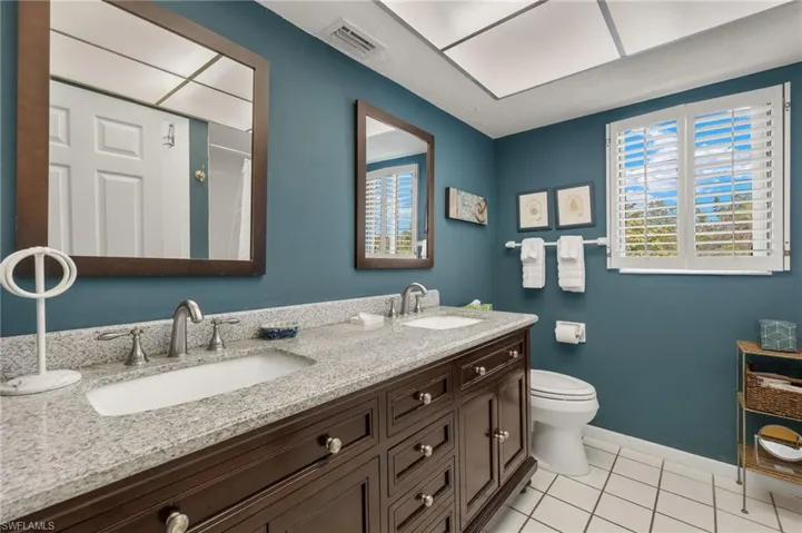 Bathroom with light tile patterned flooring, double vanity, and a shower with curtain