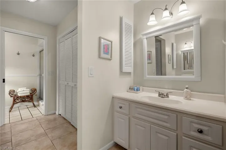Full bathroom with a closet, vanity, light tile patterned flooring, and a stall shower