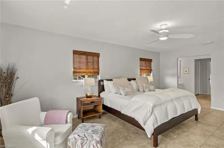 Tiled bedroom with multiple windows and a ceiling fan