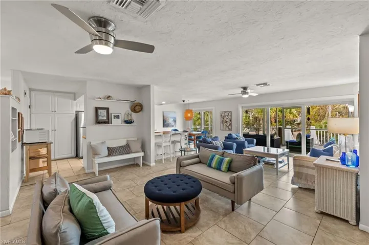 Living area featuring a textured ceiling, a ceiling fan, and light tile patterned floors