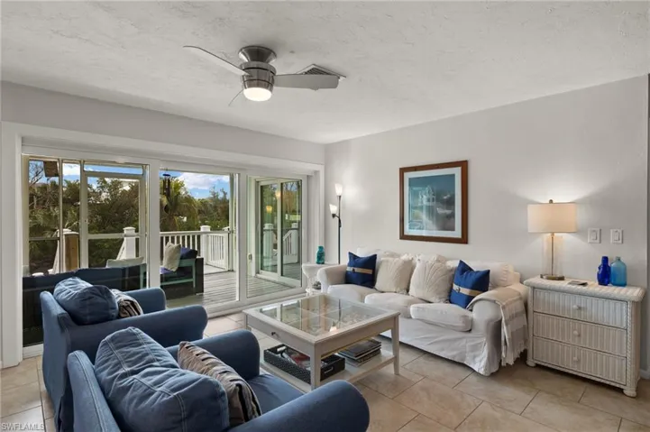 Living room featuring a textured ceiling, ceiling fan, and light tile patterned floors