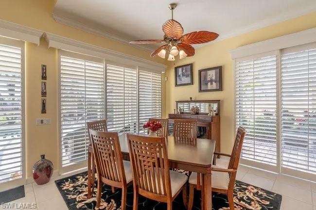 Tiled dining space with ceiling fan and ornamental molding