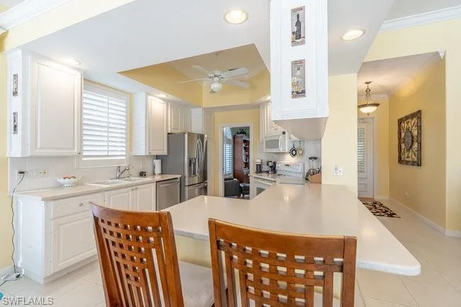 Kitchen with sink, white cabinets, appliances with stainless steel finishes, and kitchen peninsula