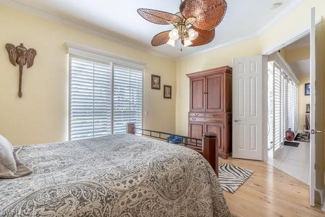 Bedroom featuring ceiling fan, crown molding, and light hardwood / wood-style floors