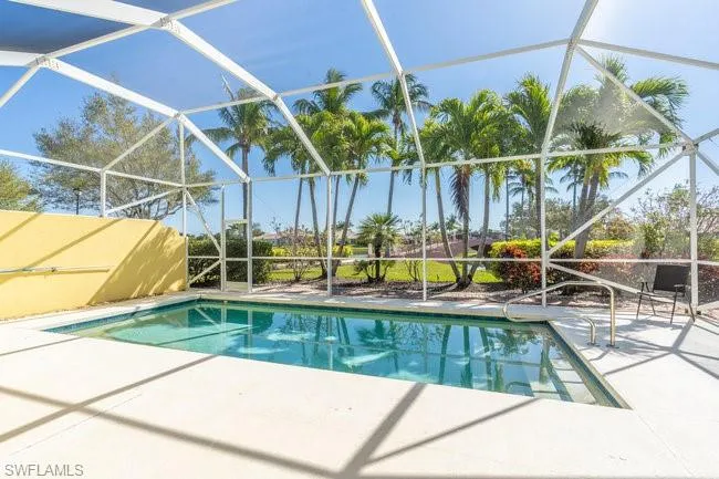 View of pool featuring glass enclosure and a patio area