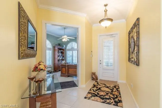 Entryway with ceiling fan, ornamental molding, and light tile patterned flooring