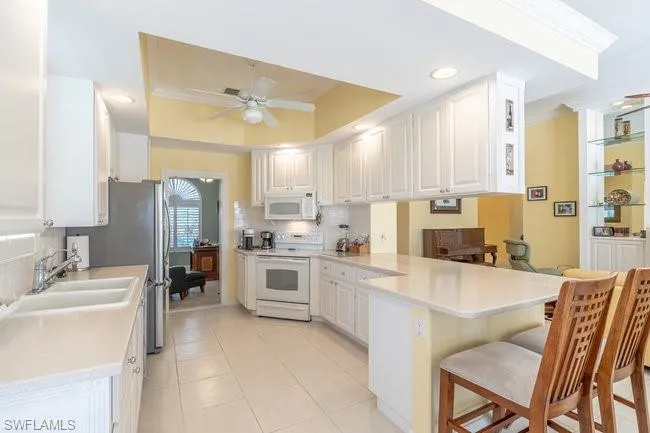 Kitchen with white cabinetry, kitchen peninsula, and white appliances