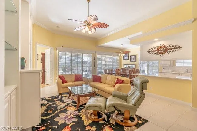 Living room featuring ceiling fan, light tile patterned floors, and ornamental molding
