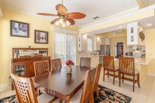 Dining space with ceiling fan, light tile patterned floors, and crown molding
