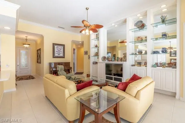 Living room featuring ceiling fan, light tile patterned floors, and crown molding