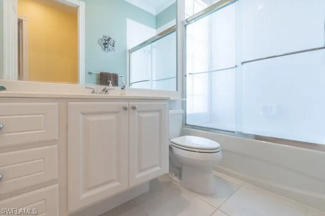 Full bathroom featuring toilet, tile patterned floors, vanity, and shower / bath combination with glass door