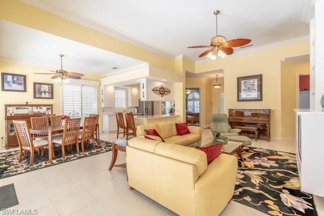 Tiled living room with ceiling fan and crown molding