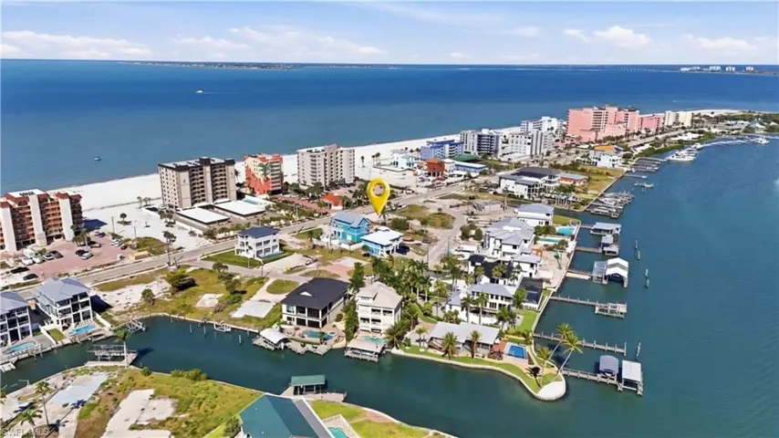 Coastal property featuring beach proximity, waterfront access with boat docks, and surrounding residential structures - Virtually Edited Image