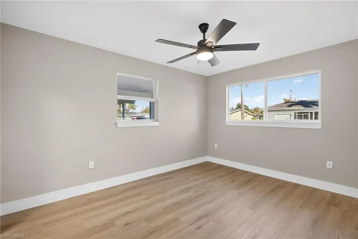 Empty room with light wood-style floors, plenty of natural light, and a ceiling fan