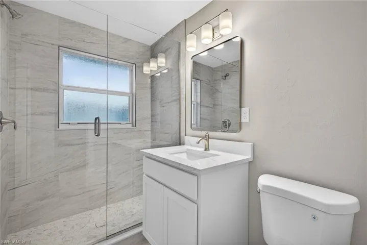 Bathroom featuring a marble finish shower, vanity, and a textured wall
