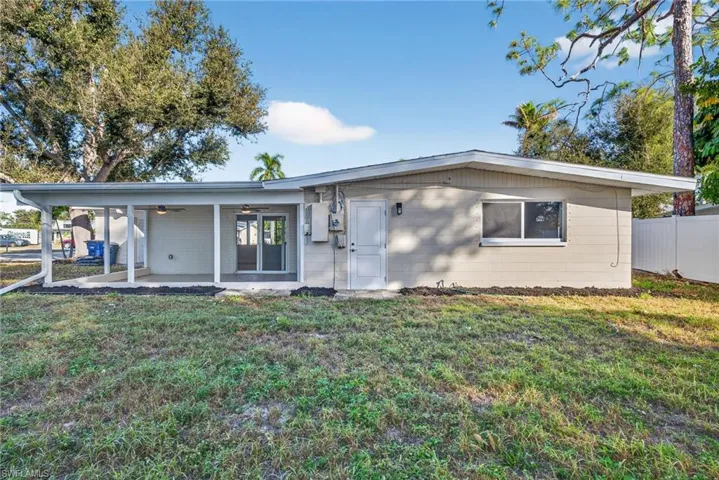 Back of property featuring ceiling fan and concrete block siding