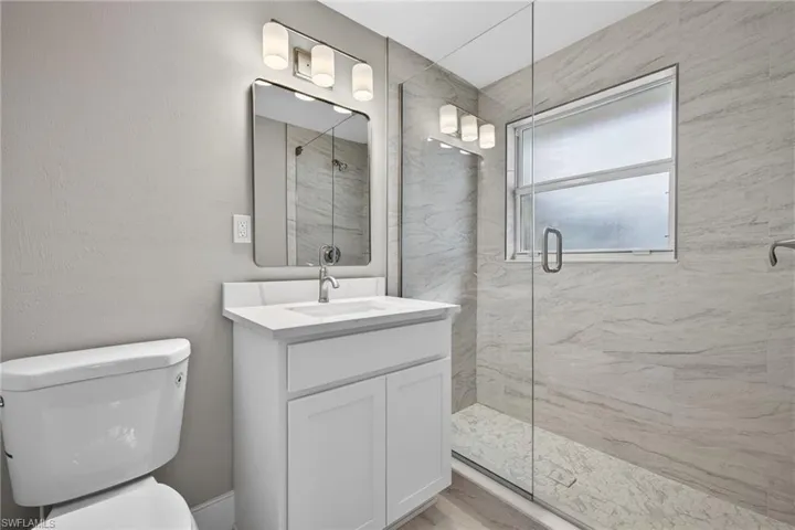 Primary bathroom featuring a marble finish shower, vanity, and a textured wall