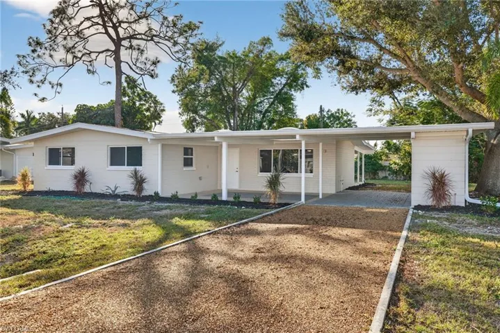 Ranch-style home featuring a front lawn and a carport