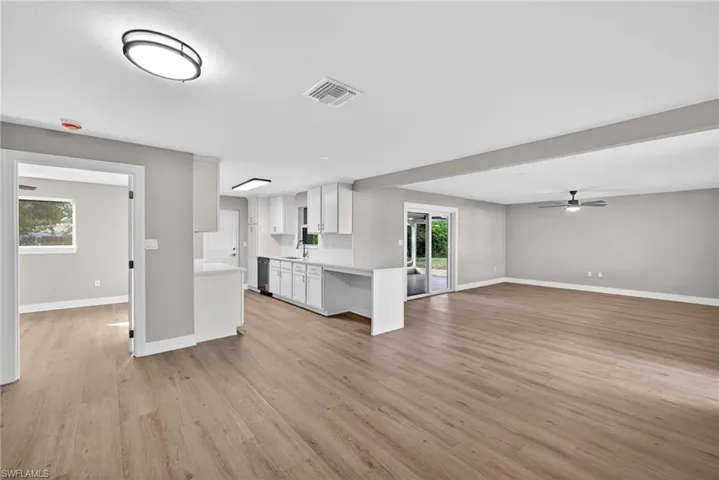 Dining Area with open floor plan, a ceiling fan, white cabinets, light wood-style floors, and a peninsula