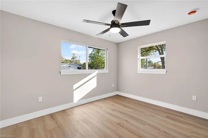 Empty room with light wood-style flooring, healthy amount of natural light, and ceiling fan