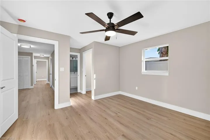 Primary bedroom with ensuite bathroom, light wood-style floors, and a ceiling fan