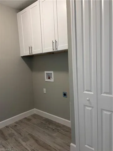 Laundry room featuring dark wood-type flooring, baseboards, cabinet space, electric dryer hookup, and washer hookup