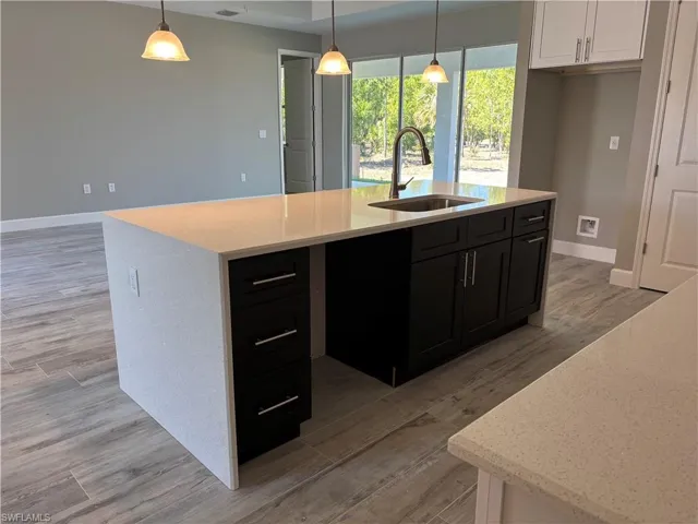 Kitchen featuring white cabinets, a sink, dark cabinets, and light wood finished floors