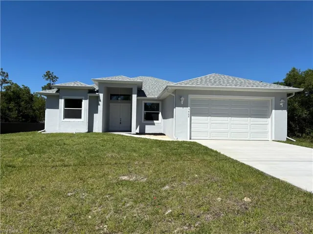 Home with a front lawn, driveway, stucco siding, and an attached two-car garage