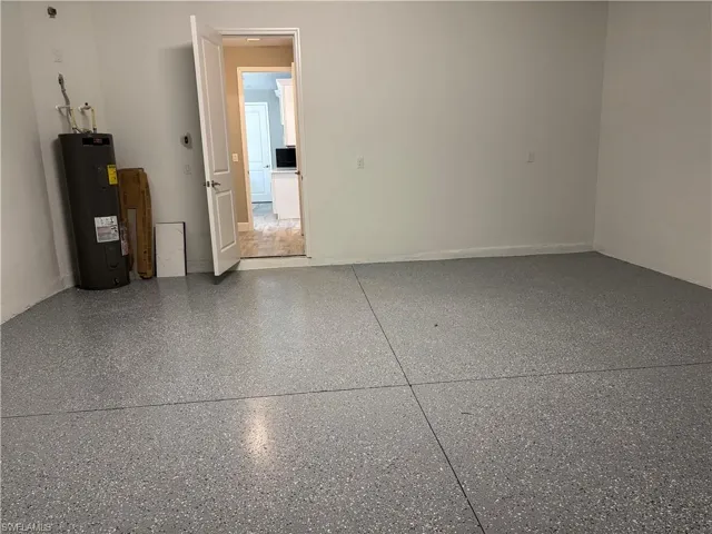 Spare room featuring water heater and speckled floor