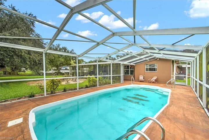 View of pool with glass enclosure and a patio area