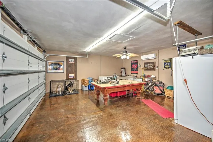 Garage with a workshop area, ceiling fan, white fridge, and an AC wall unit