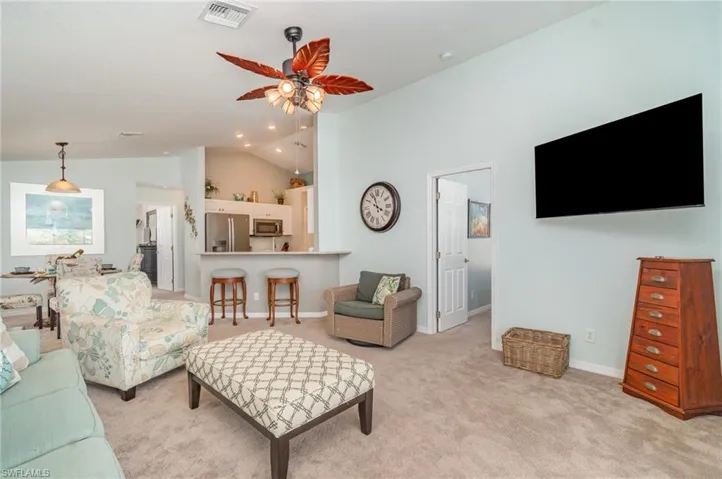 Living room featuring light colored carpet, ceiling fan, and high vaulted ceiling