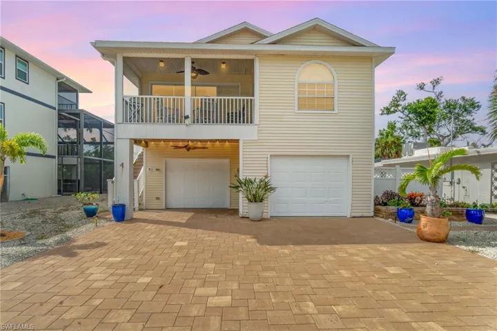 View of front  ceiling fan, pavers for  driveway, an attached large garage, and a screened in balcony