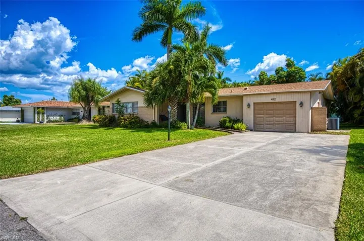 Ranch-style house with concrete driveway, central air condition unit, a front lawn, and a garage