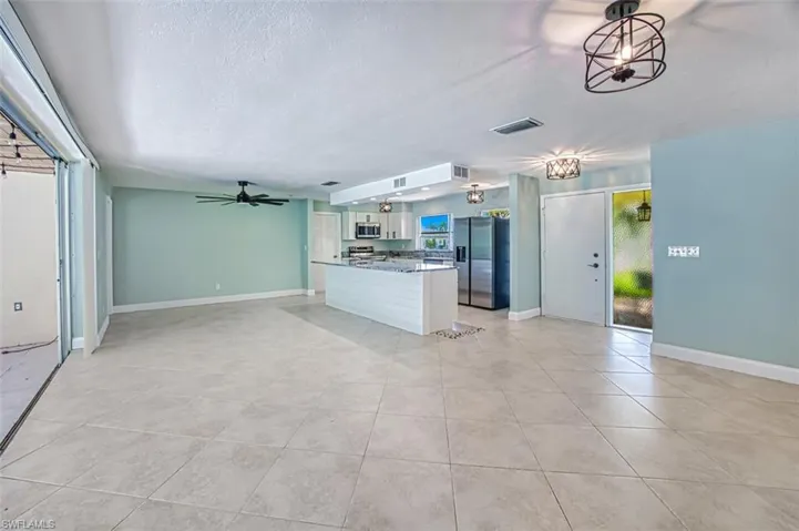 Unfurnished living room featuring light tile patterned flooring, a ceiling fan, and baseboards