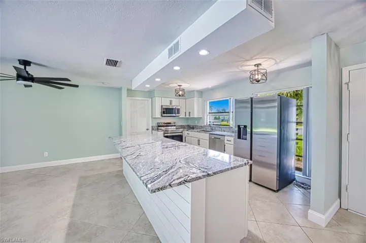 Kitchen featuring light stone counters, white cabinetry, a sink, visible vents, and stainless steel appliances